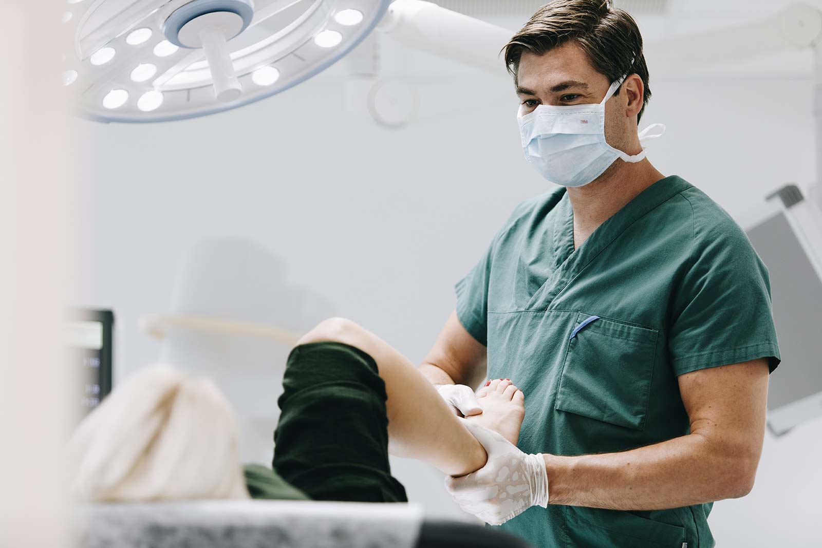 Bilde av Dr. Erik Bjørbæk som behandler en pasient inne på et behandlingsrom, han gjør bevegelser i ankelen til pasienten - Stamcelleklinikken - Artrose